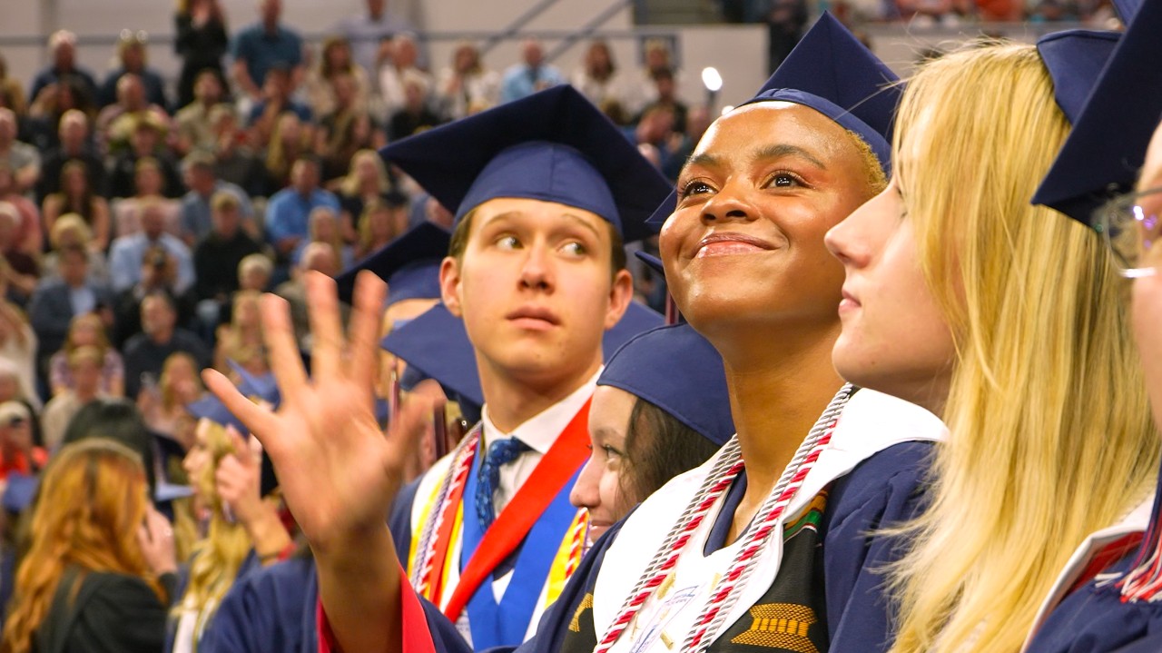 An Academy District 20 graduate smiles and waves during the ceremony.